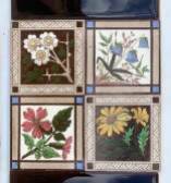 Detail of uncommon Steele and Wood, England. deep brown hand tinted print feature tiles. Aesthetic Movement design with four different flowers framed in quandrants. Flower colours white, blue, pink and yellow. Made between late 1870s - mid 1890s. Deep chocolate brown 3 x 6 inch spacer tiles, Two panel fireplace set $420 (OTB321) salvaged vintage recycled, demolition, reproduction, restoration, home renovation secondhand, used , original, old, reclaimed, heritage, antique, victorian, art nouveau edwardian georgian art deco